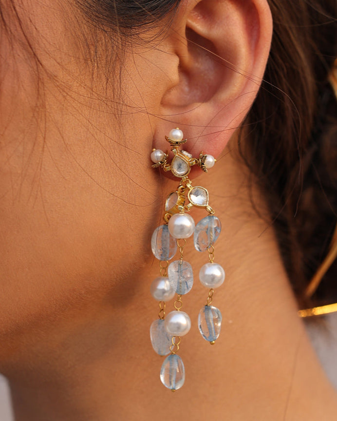 Close-up of a woman wearing gold earrings with clear stones.